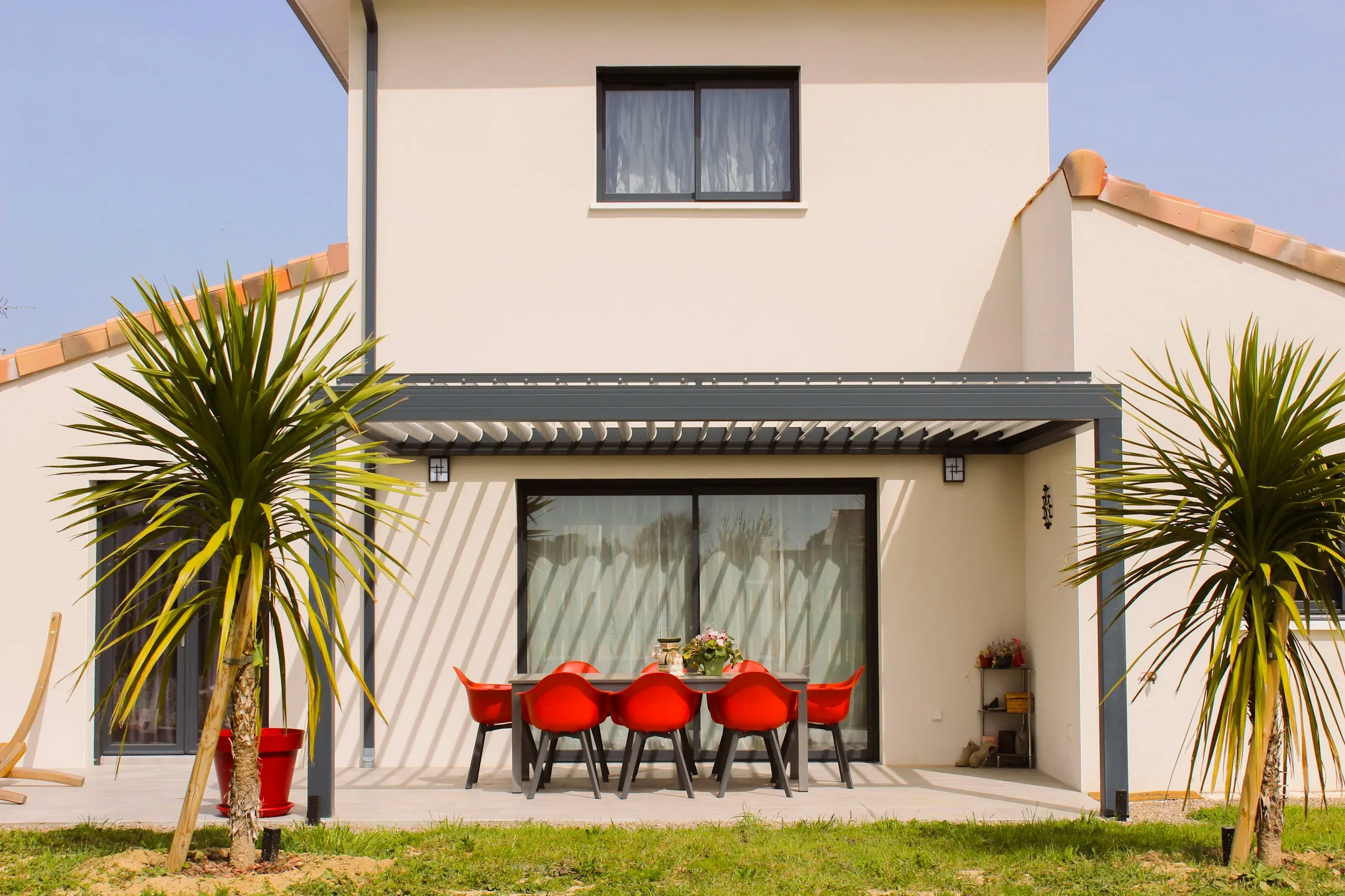 Pergola adossée à une maison, au-dessus d’une table de jardin