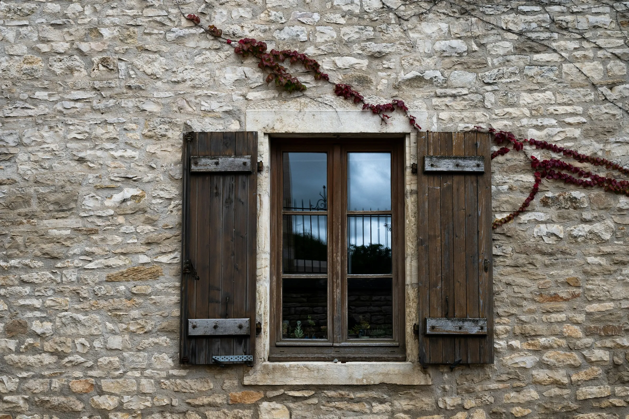 Volets battants en bois sur un mur en pierre, longère